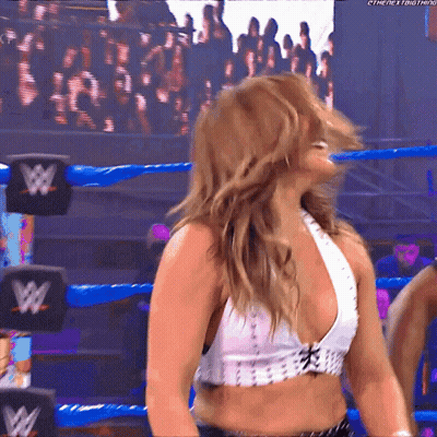 A Woman In A Wrestling Ring Is Wearing A White Top With A W Logo On It GIF
