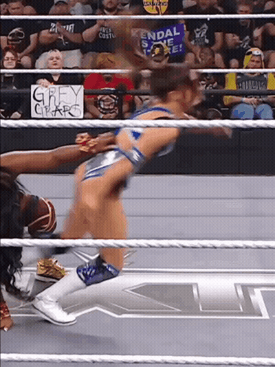 A Woman In A Wrestling Ring With A Sign Behind Her That Says Grey Claw GIF