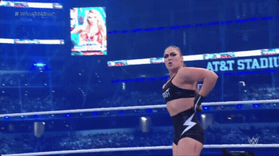 A Woman In A Wrestling Ring With A Sign That Says At & T Stadium In The Background GIF