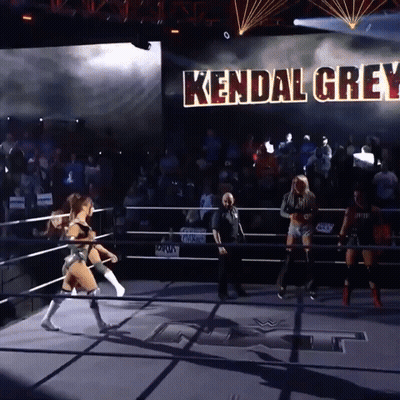 A Woman In A Wrestling Ring With Kendal Grey Written On A Large Screen Behind Her GIF
