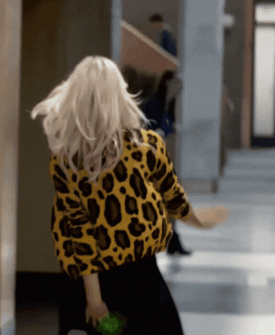 A Woman In A Yellow And Black Leopard Print Sweater GIF
