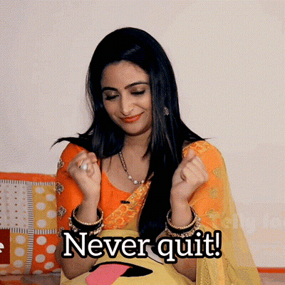 A Woman In A Yellow And Orange Dress Says " Never Quit " With Her Hands In The Air GIF