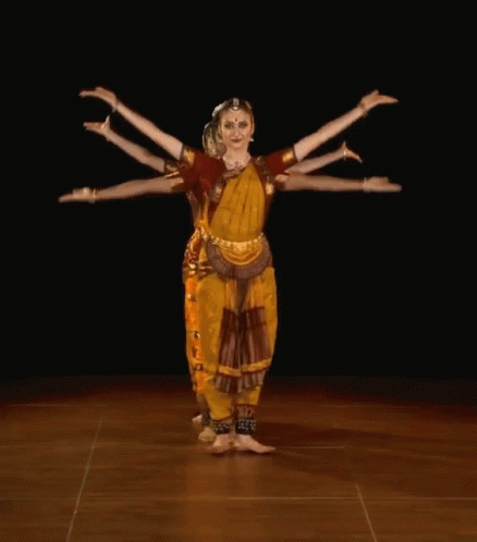 A Woman In A Yellow And Red Outfit Is Dancing GIF