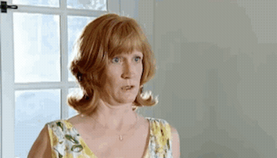 A Woman In A Yellow And White Floral Dress Is Standing In Front Of A Window . GIF