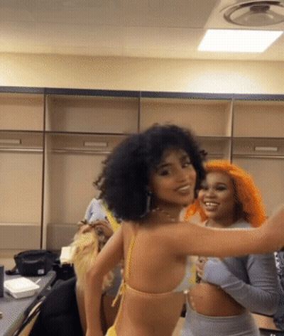 A Woman In A Yellow Bikini Is Standing Next To Another Woman With Orange Hair GIF