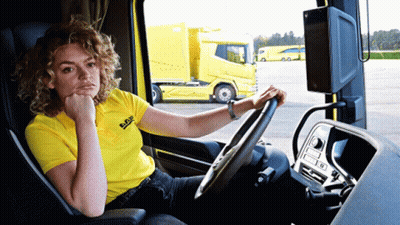 A Woman In A Yellow Daf Shirt Sits In A Truck GIF