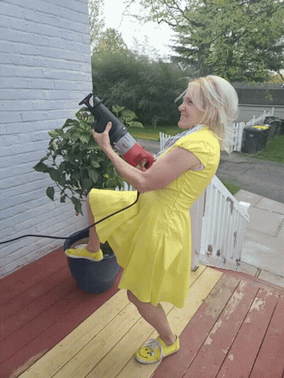 A Woman In A Yellow Dress Holds A Red Saw GIF