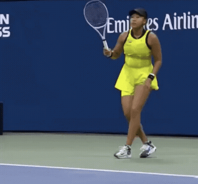 A Woman In A Yellow Dress Is Holding A Tennis Racquet GIF