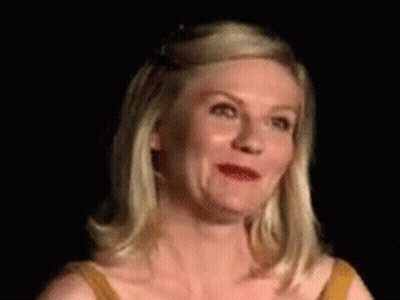 A Woman In A Yellow Dress Is Making A Funny Face In A Dark Room . GIF