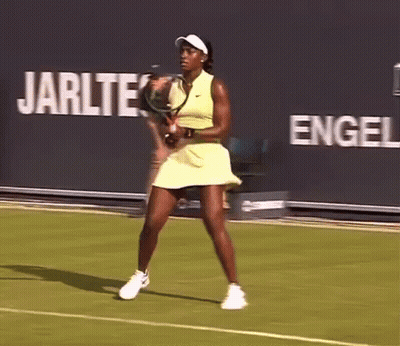 A Woman In A Yellow Dress Is Playing Tennis On A Court GIF
