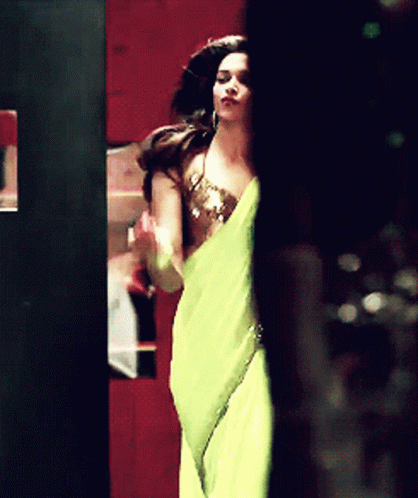 A Woman In A Yellow Dress Is Standing In A Dark Room GIF