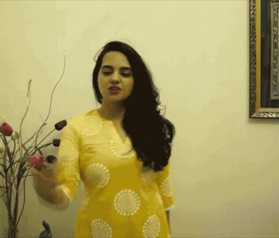 A Woman In A Yellow Dress Is Standing In Front Of A Picture Frame GIF