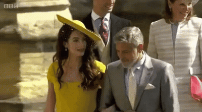 A Woman In A Yellow Dress Is Walking With A Man In A Suit And Tie . GIF