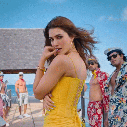 A Woman In A Yellow Dress Stands In Front Of A Group Of People GIF