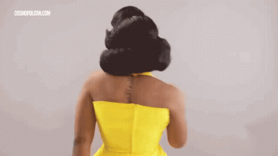 A Woman In A Yellow Dress With A Tattoo On Her Back Is Standing With Her Back To The Camera . GIF