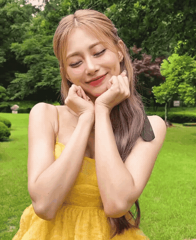 A Woman In A Yellow Dress With Her Hands On Her Face GIF