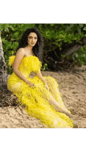 A Woman In A Yellow Feathered Dress Is Sitting On The Sand . Sticker