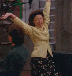 A Woman In A Yellow Jacket Is Dancing In A Room GIF