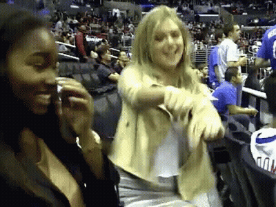 A Woman In A Yellow Jacket Is Dancing In A Stadium GIF