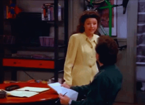 A Woman In A Yellow Jacket Is Standing Next To A Man In A Green Shirt . GIF