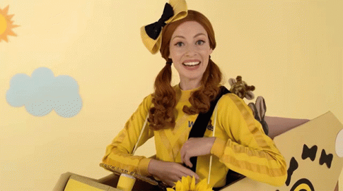 A Woman In A Yellow Outfit Is Sitting In A Box GIF