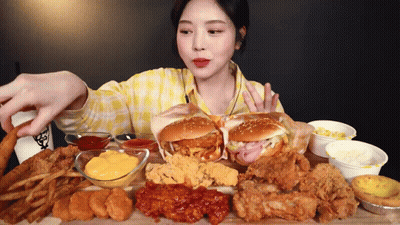 A Woman In A Yellow Plaid Shirt Is Eating A Lot Of Fried Food GIF