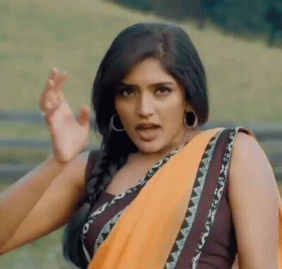 A Woman In A Yellow Saree Is Making A Funny Face While Standing In A Field . GIF