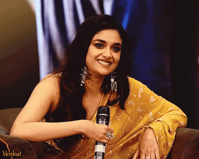 A Woman In A Yellow Saree Is Smiling While Holding A Microphone And The Word Venkat Is On The Bottom Right GIF