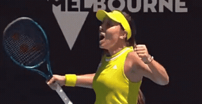 A Woman In A Yellow Shirt Is Holding A Tennis Racquet And Celebrating . GIF