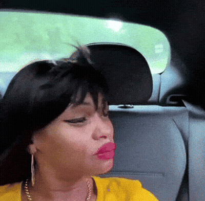 A Woman In A Yellow Shirt Is Sitting In The Back Seat Of A Car With Her Eyes Closed GIF