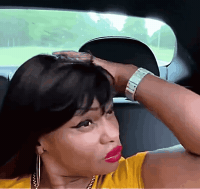 A Woman In A Yellow Shirt Is Sitting In The Back Seat Of A Car With Her Hand On Her Head GIF