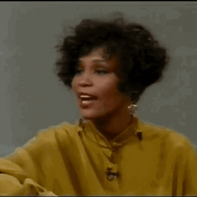 A Woman In A Yellow Shirt Is Smiling And Laughing . GIF