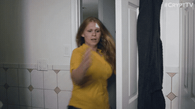 A Woman In A Yellow Shirt Is Standing In A Doorway With #Crypttv Written On The Bottom Right GIF