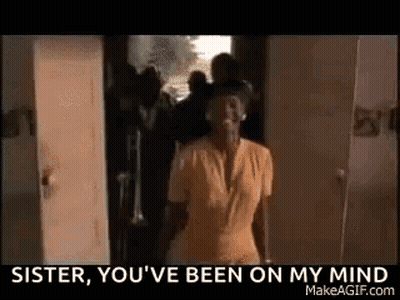 A Woman In A Yellow Shirt Is Standing In Front Of A Door And A Group Of Men . GIF