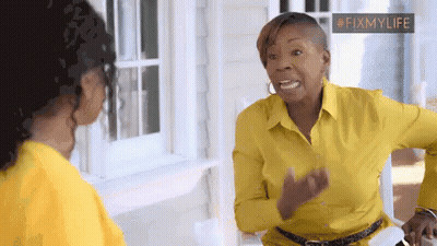 A Woman In A Yellow Shirt Is Talking To Another Woman In Front Of A Window . GIF
