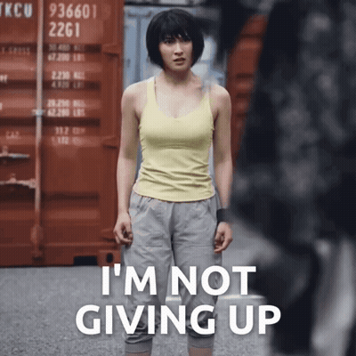 A Woman In A Yellow Tank Top Is Standing In Front Of A Red Container That Says Tkcu 2261 GIF