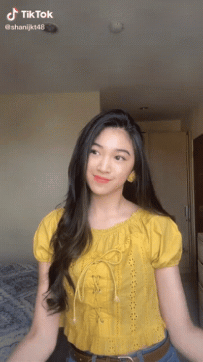 A Woman In A Yellow Top Is Dancing In A Room With A Tiktok Watermark GIF