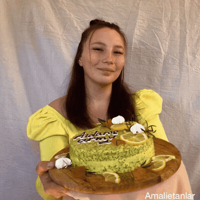 A Woman In A Yellow Top Is Holding A Cake That Says Adam 'S Curry GIF