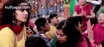 A Woman In A Yellow Top Is Standing In Front Of A Crowd Of People With The Website Kulfyapp.com In The Corner GIF