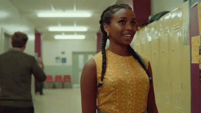 A Woman In A Yellow Top Stands In A Hallway Next To Lockers GIF