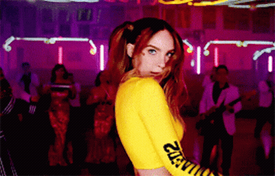 A Woman In A Yellow Top With The Word Caution On The Sleeves GIF