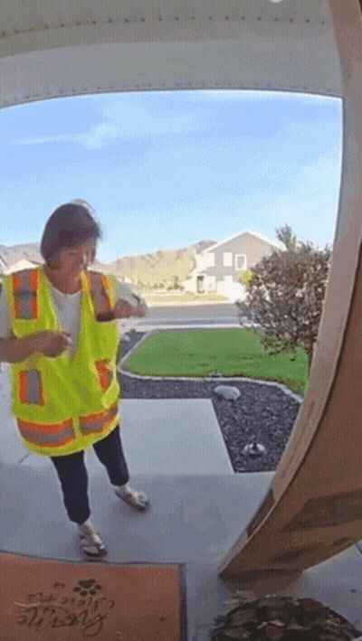 A Woman In A Yellow Vest Is Standing In Front Of A Door With A Welcome Mat GIF