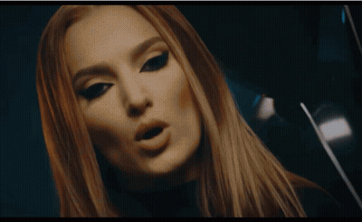 A Woman In A Zebra Print Shirt Touches A Large Screen GIF