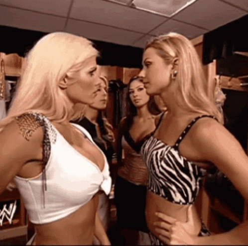 A Woman In A Zebra Print Top Stands Next To Another Woman GIF