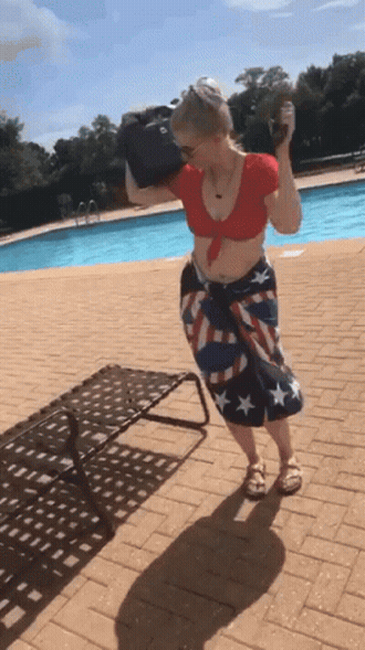 A Woman In An American Flag Skirt Is Standing By A Pool GIF