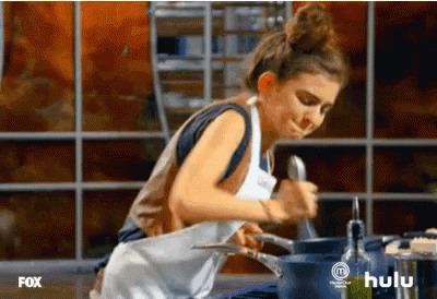 A Woman In An Apron Is Cooking In A Kitchen With A Hulu Logo In The Corner GIF