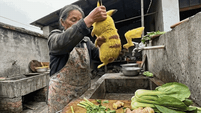 A Woman In An Apron Is Holding A Yellow Animal Over A Cutting Board GIF