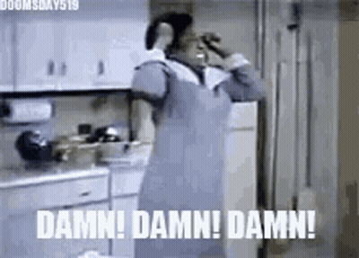 A Woman In An Apron Is Standing In A Kitchen Talking On A Cell Phone And Making A Funny Face . GIF