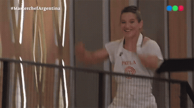 A Woman In An Apron Is Standing On A Balcony With Her Arms Outstretched And Smiling . GIF