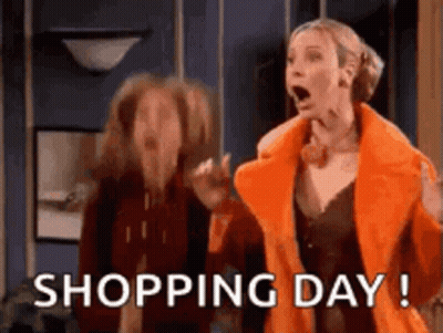 A Woman In An Orange Coat Is Standing Next To Another Woman In A Room . GIF